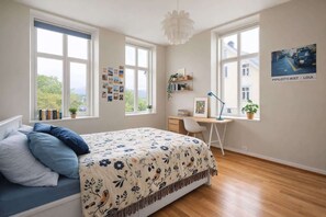 A bedroom with a bed, desk, and large windows. - Modern Apartment, Panoramic View in Heart of Bergen (Bergenhus)