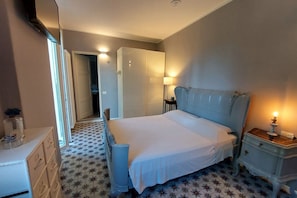 A bedroom with a bed, dresser, nightstand, and a door leading to another room.