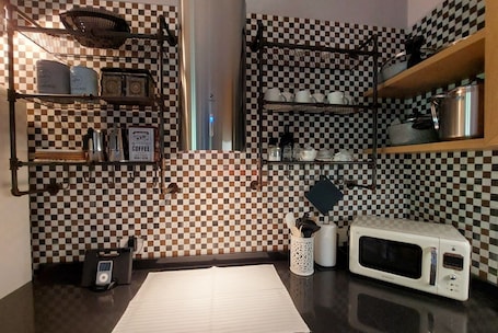 Una cucina con zoccolo a scacchi, scaffali con stoviglie, un forno a microonde e una macchina per il caffè.. Acquazzurra, luxury duplex, pool, parking space, free WiFi