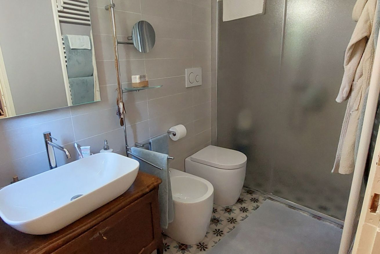 Une salle de bain avec un lavabo blanc, des toilettes, une douche et un miroir.