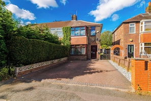 A residential street with houses, a paved driveway, and a hedge. - 2 Bed House with Driveway & Workspace  (Manchester)