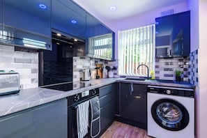 A modern kitchen with a built-in washer, a toaster, and a window with blinds. - 2 Bed House with Driveway & Workspace  (Manchester)