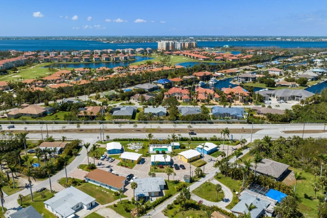 A coastal residential area with multiple buildings, a large body of water, and a road.
