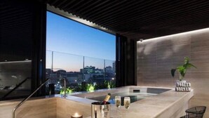 Ein modernes Badezimmer mit großem Fenster, einer Badewanne, einer Champagnerflasche und Gläsern.