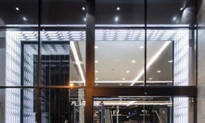 Ein modernes Gebäude mit großen Glasfenstern, einem Metallgerüst und einem sichtbaren Aufzug.