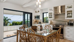 Una cocina moderna con muebles blancos, una isla grande y vista al océano.