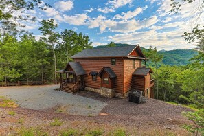 Eine Holzhütte mit Stein Fundament, einer Veranda und einer Schotterzufahrt.