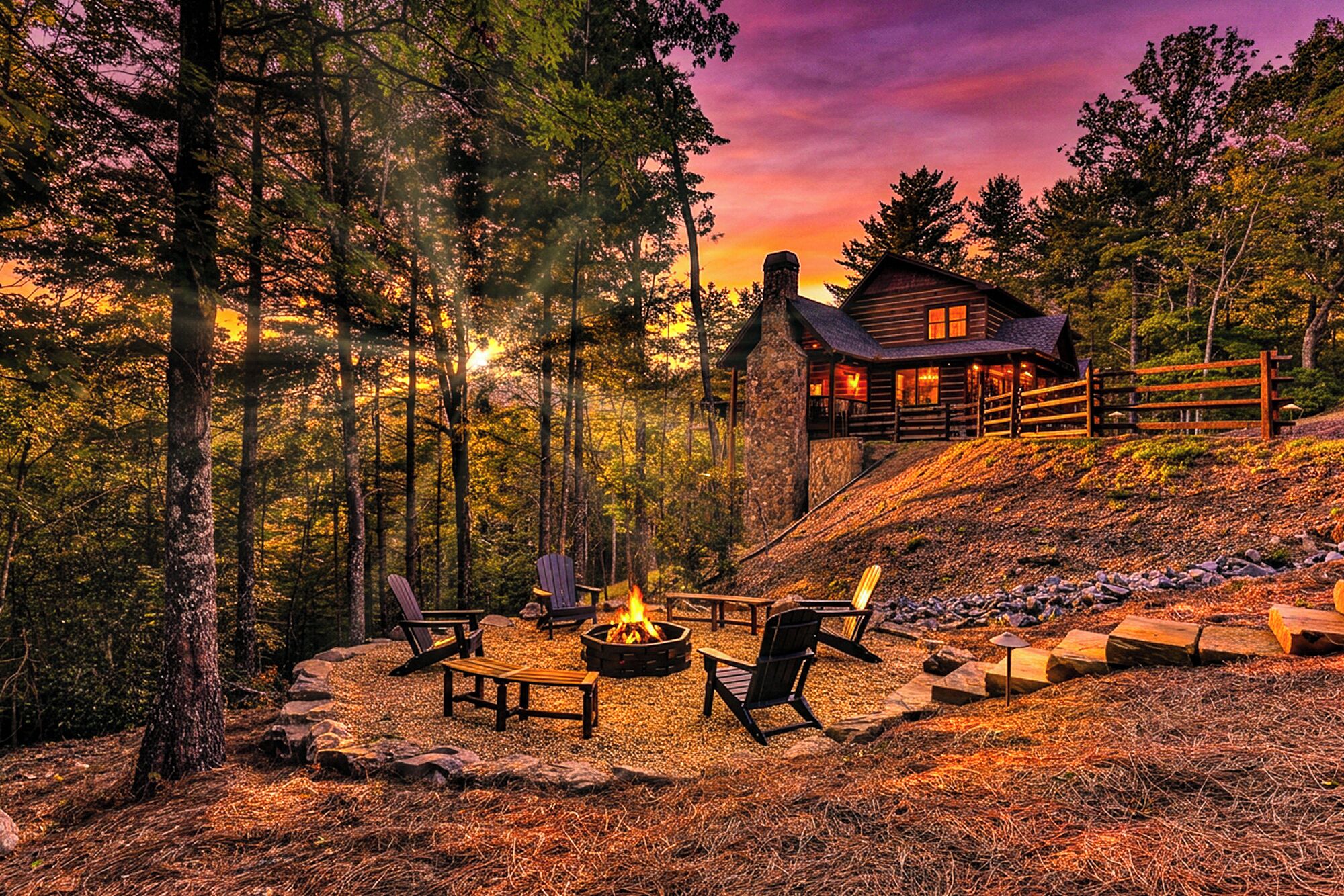 A cabin with a fire pit and outdoor seating, surrounded by trees.