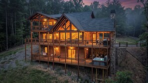 Eine zweistöckige Blockhütte mit Balkon, Whirlpool und Steinofen.
