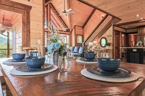 A wooden dining table with blue bowls and clear glasses, a staircase, and a view of the outdoors. - Aska Timber Lodge | Blue Ridge, GA (Cherry Log)