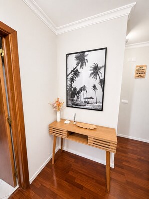 Un escritorio de madera con un florero y un marco de fotos frente a una pared blanca.