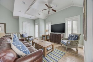 A living room with a ceiling fan, a television, a sofa, a coffee table, and a chair. - 1327 - Seaglass Retreat, Corolla Retreat | Hot Tub, Pool & 4BR Comfort (Corolla)