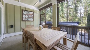 A wooden table and chairs in a covered outdoor area with a view of trees. - 1327 - Seaglass Retreat, Corolla Retreat | Hot Tub, Pool & 4BR Comfort (Corolla)
