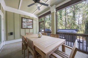 A wooden table and chairs in a covered outdoor area with a view of trees. - 1327 - Seaglass Retreat, Corolla Retreat | Hot Tub, Pool & 4BR Comfort (Corolla)