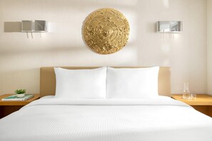 Ein Hotelzimmer mit einem großen Bett, zwei Nachttischen, einer Wanddekoration und einer kleinen Pflanze.
