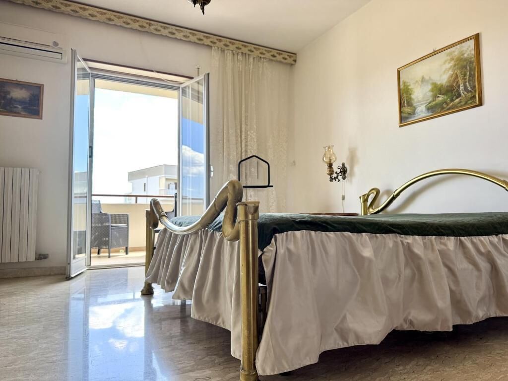 Una habitación con una cama, una ventana con cortinas, un cuadro en la pared y vistas al exterior.