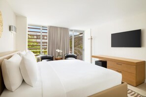 Ein Hotelzimmer mit Bett, Schreibtisch, Stuhl, Fernseher und einem Fenster mit Jalousien.