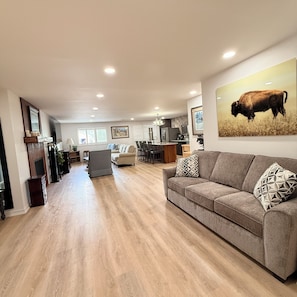 A spacious living area with a sofa, a dining table, and a kitchen in the background.