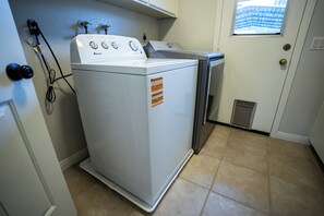 Une buanderie équipée d’un lave-linge et d’un sèche-linge à chargement frontal, d’une fenêtre et d’une porte dotée d’un judas.