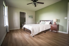 Une chambre à coucher avec un lit, une table de chevet et un ventilateur de plafond.