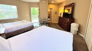 A hotel room with two beds, a ceiling fan, a TV, a dresser, a chair, and a window. - Right Direction Rentals 2 Bedroom Villa 8231 (Port St. Lucie)