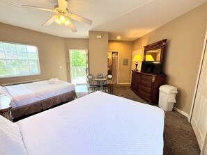 A hotel room with two beds, a ceiling fan, a TV, a dresser, a chair, and a window. - Right Direction Rentals 2 Bedroom Villa 8231 (Port St. Lucie)