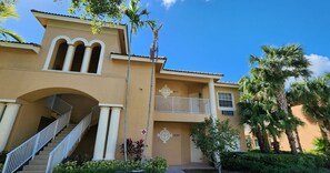 A building with a staircase, a balcony, and palm trees. - Right Direction Rentals 2 Bedroom Villa 8231 (Port St. Lucie)