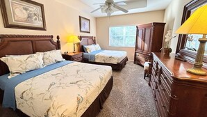 Een hotelkamer met twee bedden, een plafondventilator, een raam en een dressoir.