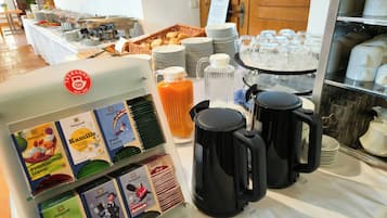 A buffet setup with various food items, coffee machines, and beverage dispensers.