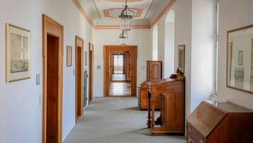 Un pasillo con puertas de madera, un aparador de madera y cuadros enmarcados en las paredes.