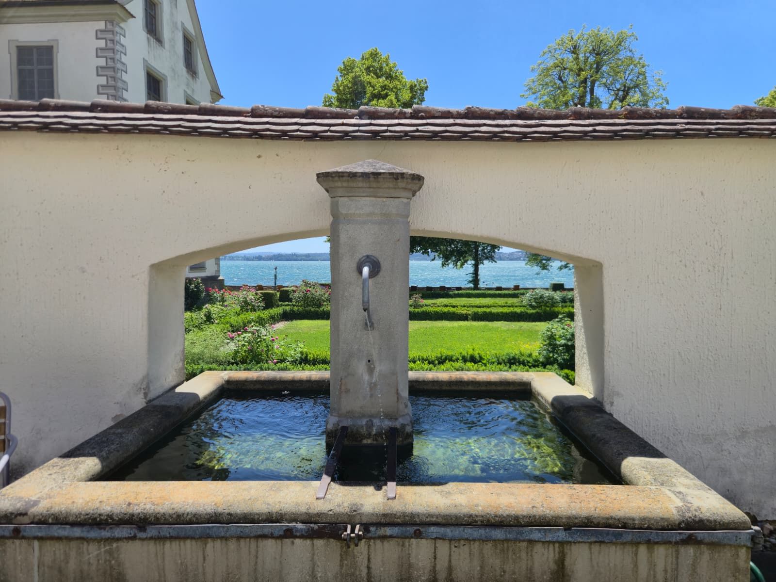 A fountain with a clear view of a lake and greenery in the background.
