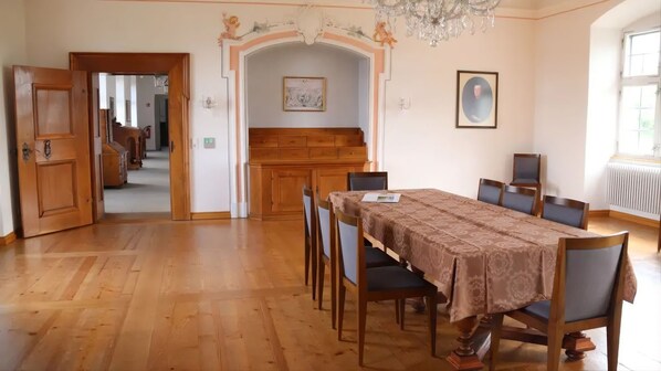 Un comedor con una mesa y sillas de madera, una araña y vista a otra habitación.