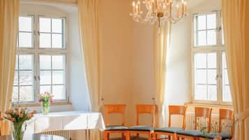 A dining room with a chandelier, wooden chairs, a round table, and a window with curtains.