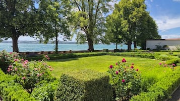 A landscaped garden with a view of a body of water, neatly trimmed hedges, and flowering plants.