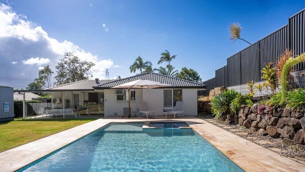 A swimming pool with a house in the background. - 4BR Luxury Retreat (Gold Coast)