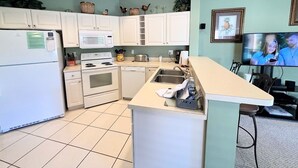 Cocina compacta con armarios blancos, un microondas, una estufa y un lavabo.