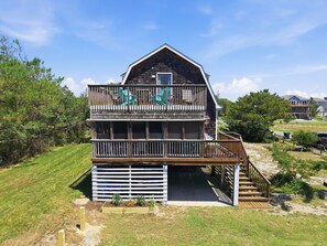 A two-story wooden house with a balcony, a covered deck, and a small garden area. - 3BR Duck cottage in Sound Sea, near the beach and Duck village. (Duck)
