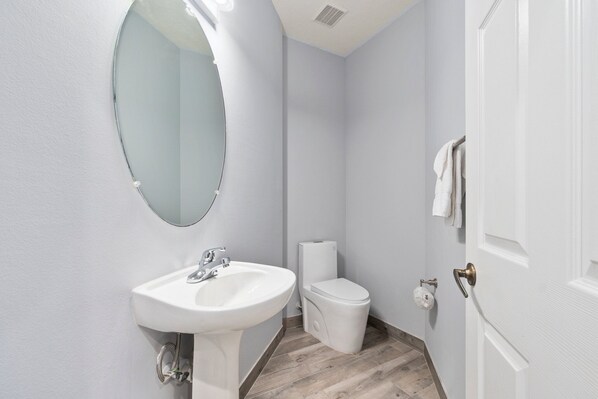 A bathroom with a white sink, toilet, and mirror.
