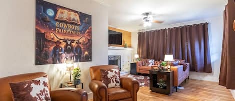 A living room with leather sofas, a fireplace, and a large poster on the wall.