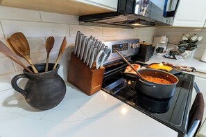 Eine Küche mit Herd, einem Topf auf dem Herd, einer Kaffeemaschine und einem Messerblock.