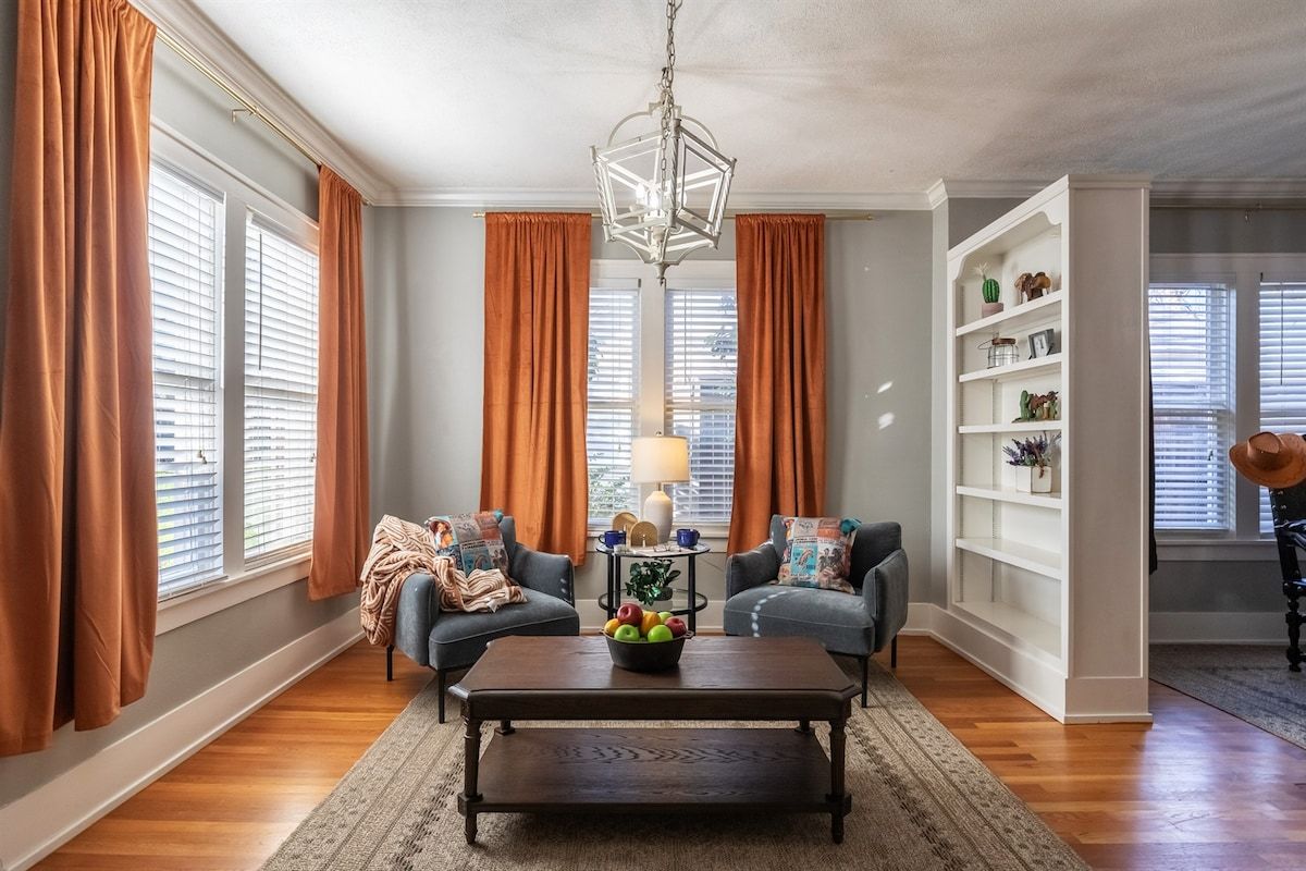 A living room with two sofas, a coffee table, a chandelier, and a bookshelf.