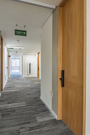 A hotel corridor with a carpeted floor, wooden doors, and a green exit sign. - Luxury boutique suite 5 stars plus free parking (Bogotá, D.C.)