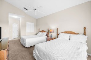 A bedroom with two beds, a ceiling fan, a lamp, and a TV. - Right Direction Rentals 2 Bedroom Villa 9906 (Port St. Lucie)