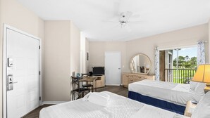 Habitació d'hotel amb dos llits, una taula de treball amb un ordinador, una televisió i un balcó amb vistes.