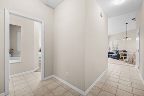 A spacious living area with a dining table and chairs, a sofa, and a kitchen area with a refrigerator. - Right Direction Rentals 2 Bedroom Villa 9906 (Port St. Lucie)