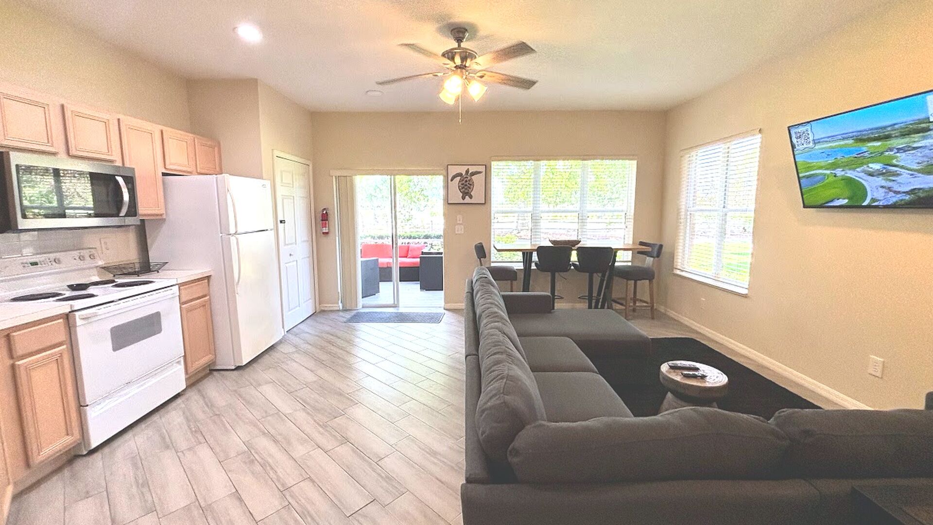 A spacious kitchen with modern appliances, a dining area with a large window, and a living room with a sofa and a TV.