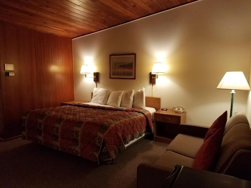 Une chambre à coucher avec un lit, deux lampes de chevet, une table de chevet, une chaise et un tableau au mur.