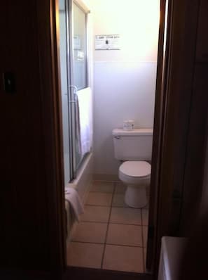 Un pasillo estrecho que conduce a un baño con un inodoro, un perchero y un letrero que indica un baño de vapor.