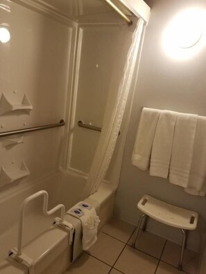 Un baño con ducha, inodoro y barras de apoyo.