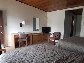 Ein Schlafzimmer mit Bett, Schreibtisch, Stuhl, Fernseher und Spiegel.